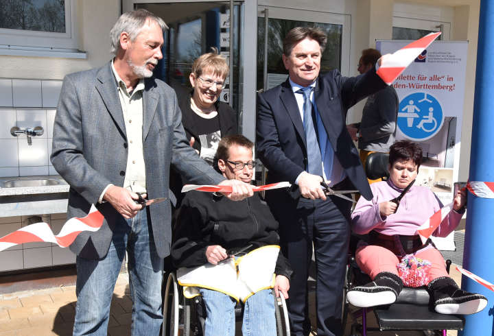 Mit einem schwungvollen Schnitt wird das Band, das noch - symbolisch - den Weg zur »Toilette für alle« versperrt, durchtrennt. V.l.n.r.: CAP-Geschäftsführer Fritz-Heinrich Bauer, LVKM-Geschäftsführerin Jutta Pagel-Steidl, Inklusionsbotschafter Daniel Linder, Sozial- und Integrationsminister Manne Lucha MdL, Inklusionsbotschafter Nathalie Gogel.<br />Foto: © Mara Sander