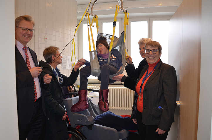 ... per Knopfdruck geht es in die Höhe! Für Inklusionsbotschafterin Theresa Birkle ist Grund, sich zu freuen. Mühelos kann sie im Hebetuch vom Rollstuhl auf die Liege schweben.<br />Foto: © Mara Sander
