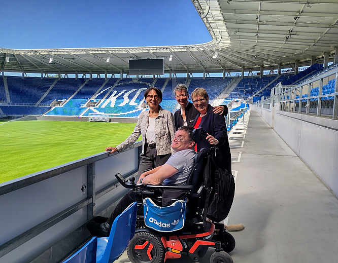Die Plätze für Fans im Rollstuhl und ihre Begleitpersonen sind überdacht und ermöglichen eine gute Sicht auf das Spielfeld. Darüber tauschen sich im Gespräch aus Fußballfan Patrick Thurn, Staatssekretärin Dr. Ute Leidig MdL, Marianne Sanschi (Betriebsleiterin des Karlsruher Eigenbetriebs „Fußballstadion im Wildpark“ und LVKM-Geschäftsführerin Jutta Pagel-Steidl (v.l.n.r.)<br>Foto: © Mara Sander