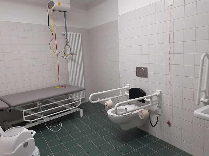 Die rund 10 qm große „Toilette für alle“  ist mit einer frei stehenden höhenverstellbare Pflegeliege, Deckenlifter und luftdicht verschließbarem Windeleimer ausgestattet.